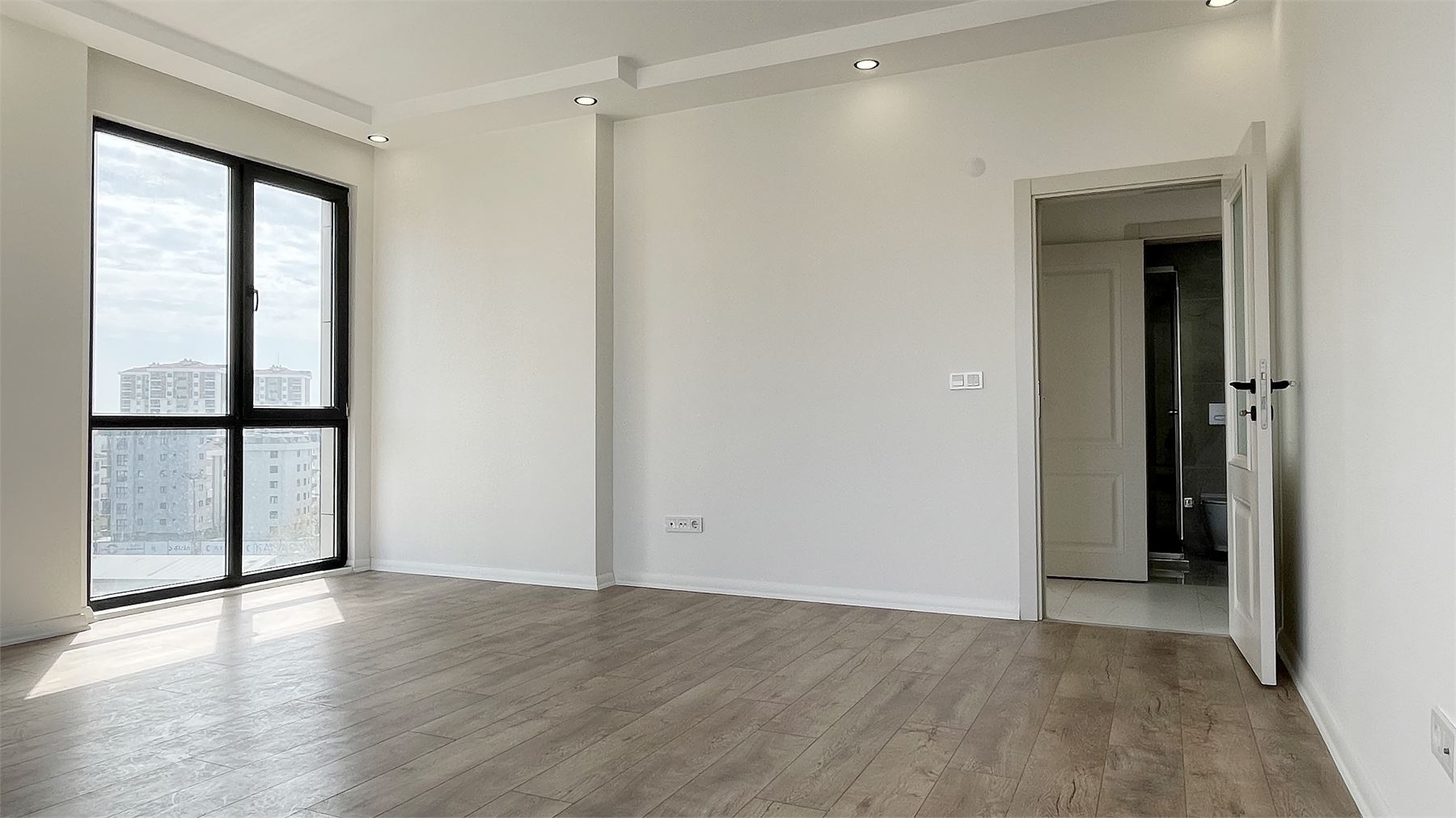 Laminat parkeli, geniş pencereli oda ve iç kapı detayı